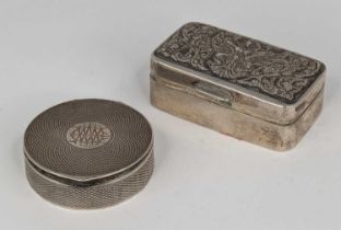 A white metal pill box of hinged rectangular form, the cover repoussee decorated with a figure of