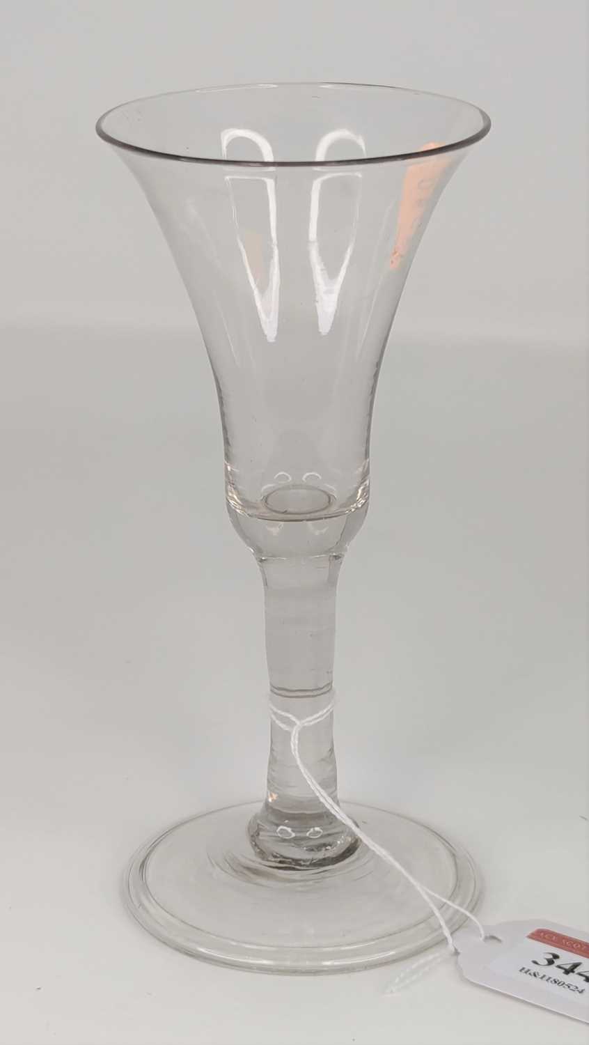 An 18th century wine glass having a trumpet shaped bowl on plain stem and domed foot with folded