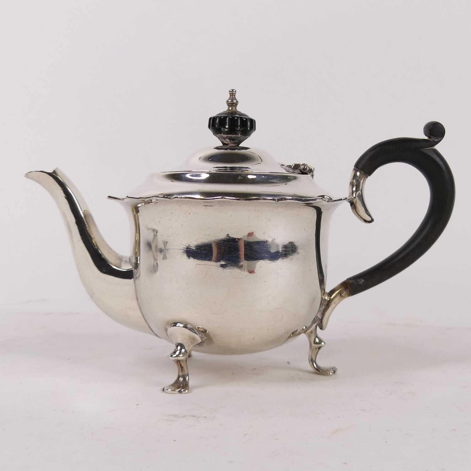 A George V silver bachelor's teapot, having ebonised finial and handle, on pad feet, maker James