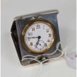 A George V silver cased travel clock, having a circular enamelled dial with Arabic numerals and