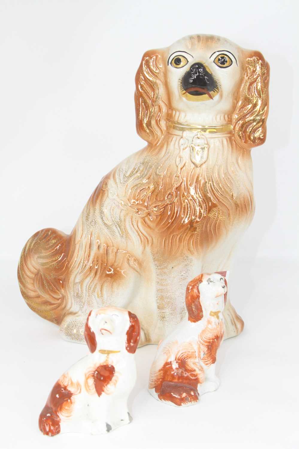 A Staffordshire pottery figure of a spaniel, height 29cm, together with two smaller