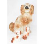 A Staffordshire pottery figure of a spaniel, height 29cm, together with two smaller