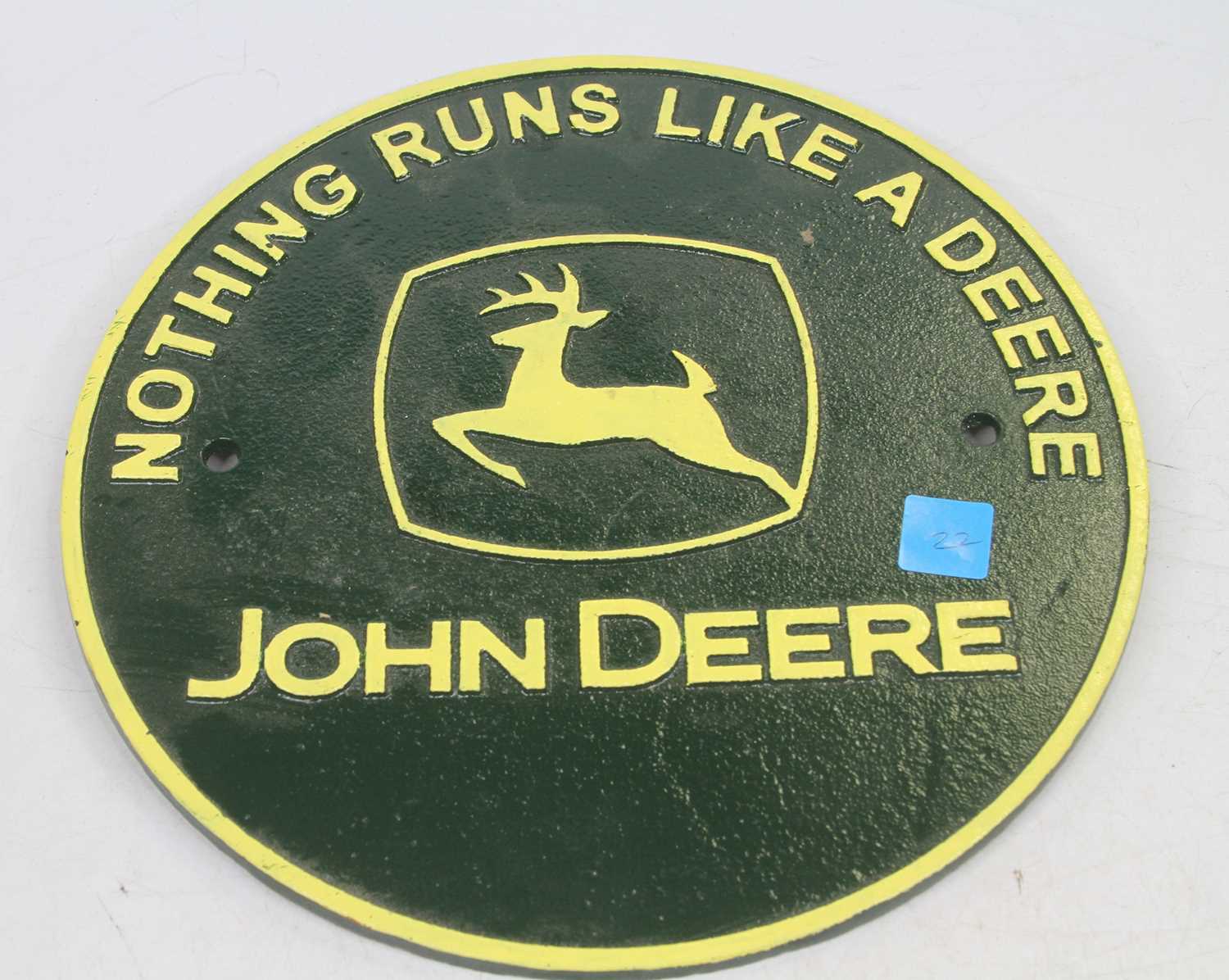 A painted cast iron circular advertising sign for John Deere inscribed Nothing Runs Like A Deere,