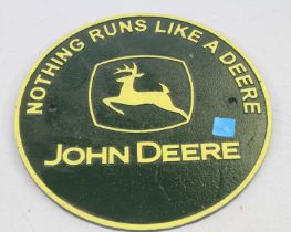 A painted cast iron circular advertising sign for John Deere inscribed Nothing Runs Like A Deere,