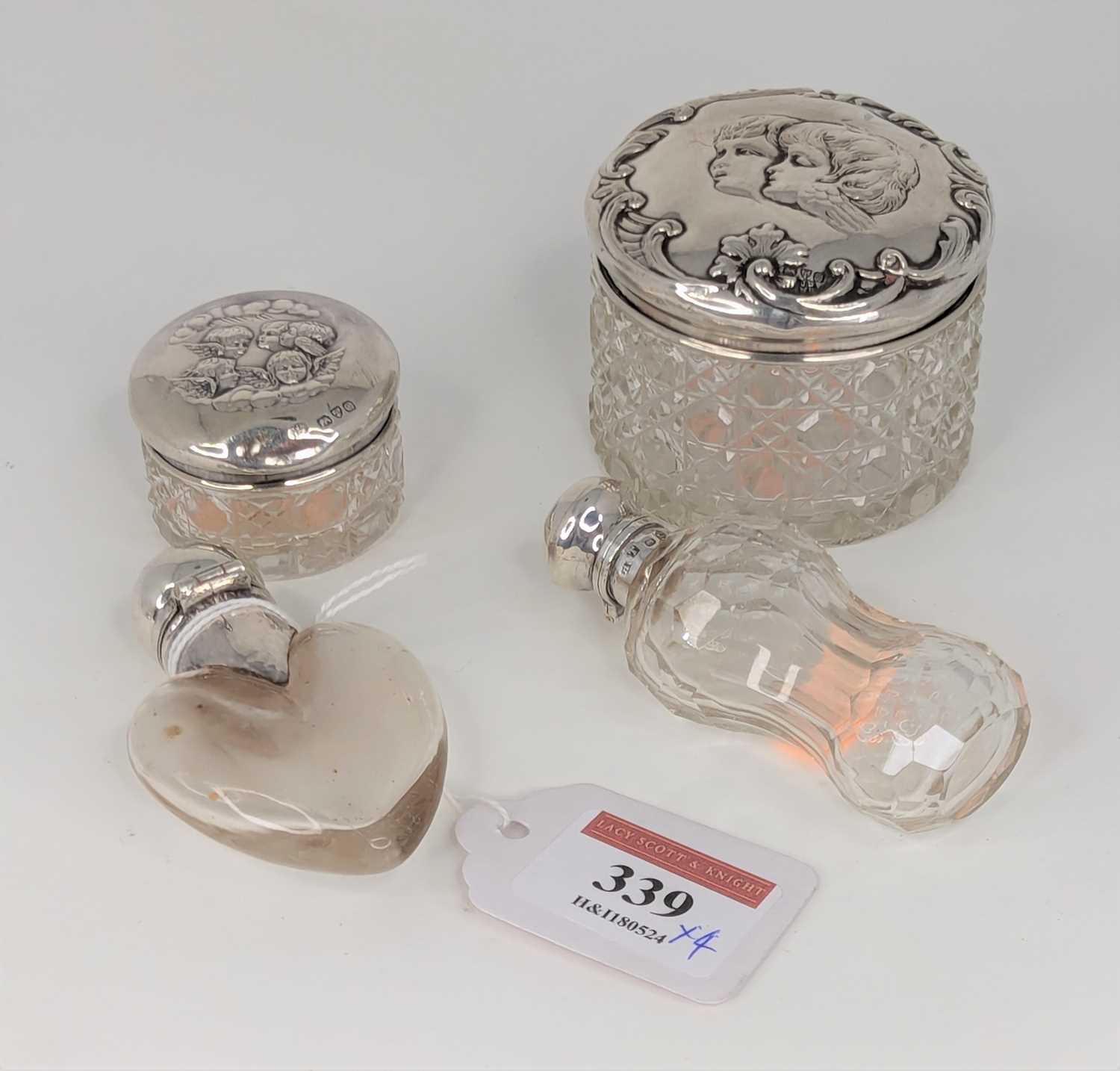 An early 20th century scent bottle, having a clear glass heart shaped body with silver cap and