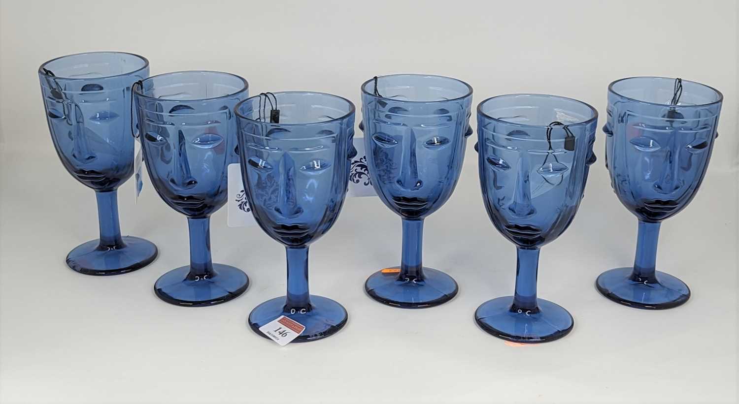 A set of six Art Deco style blue glass drinking glasses, each relief decorated with a face, height