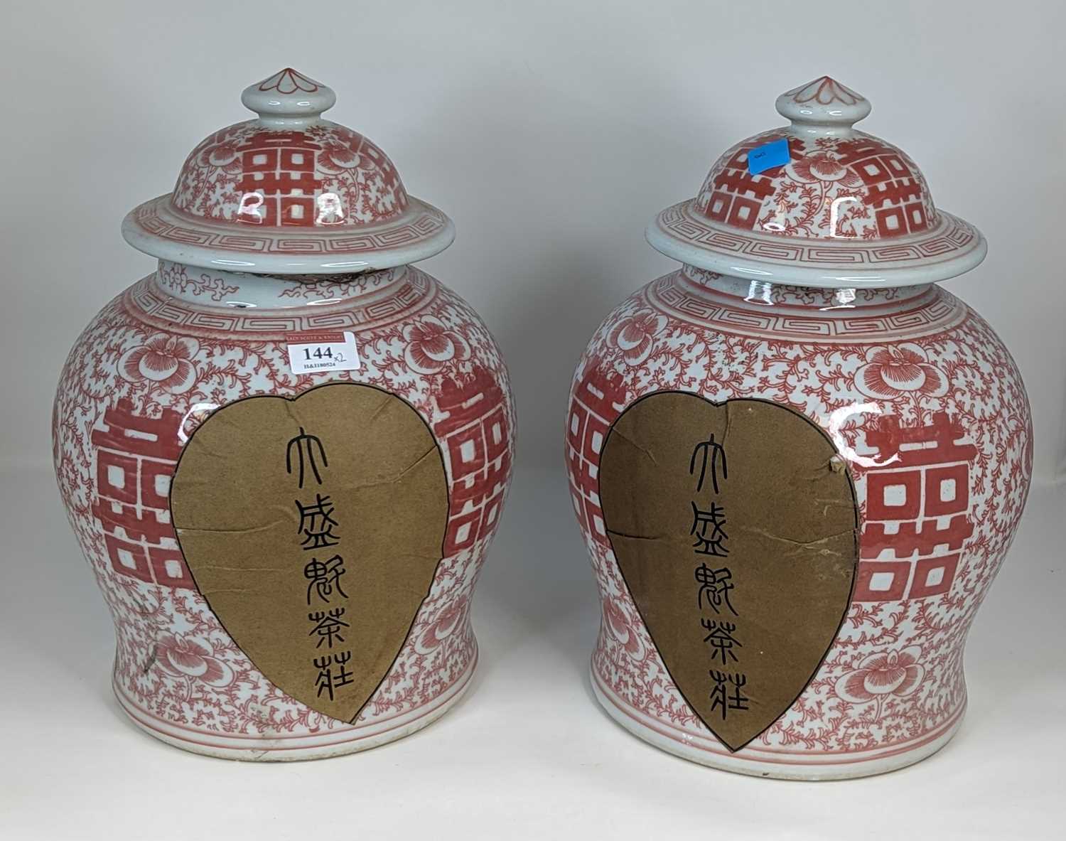 A pair of Chinese red & white glazed porcelain jars & covers, each of baluster form, decorated