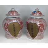 A pair of Chinese red & white glazed porcelain jars & covers, each of baluster form, decorated