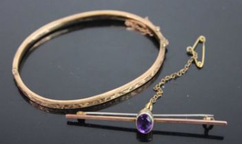 A 9ct gold and engraved hinge bangle 4.9g, dia. 6.4cm, together with a 9ct gold amethyst bar brooch,