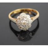 An Art Deco 18ct gold and platinum diamond tablet ring, the oval flower head setting centre set with