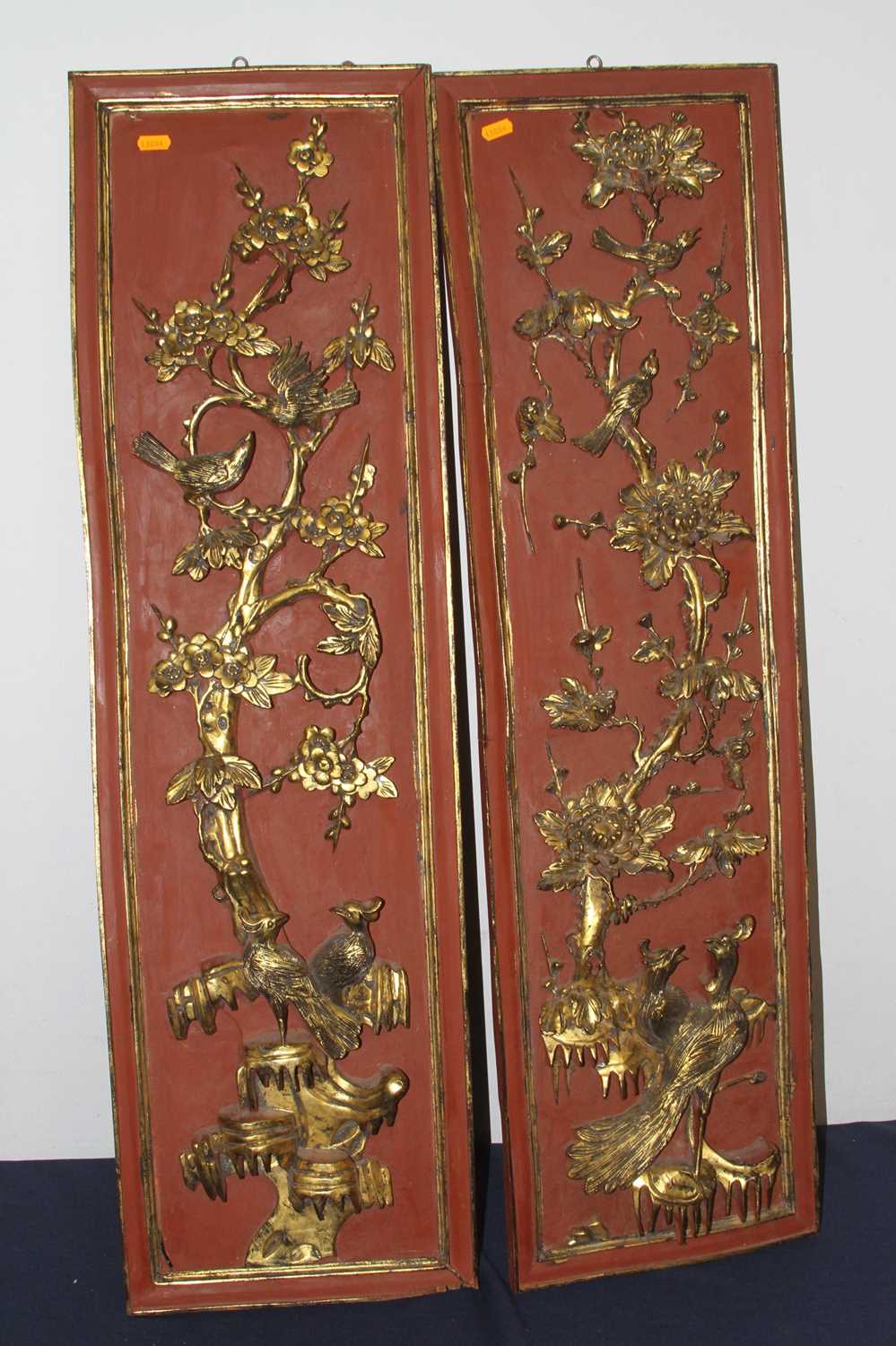 A pair of Chinese red lacquered and gilt high relief panels, each decorated with birds amongst