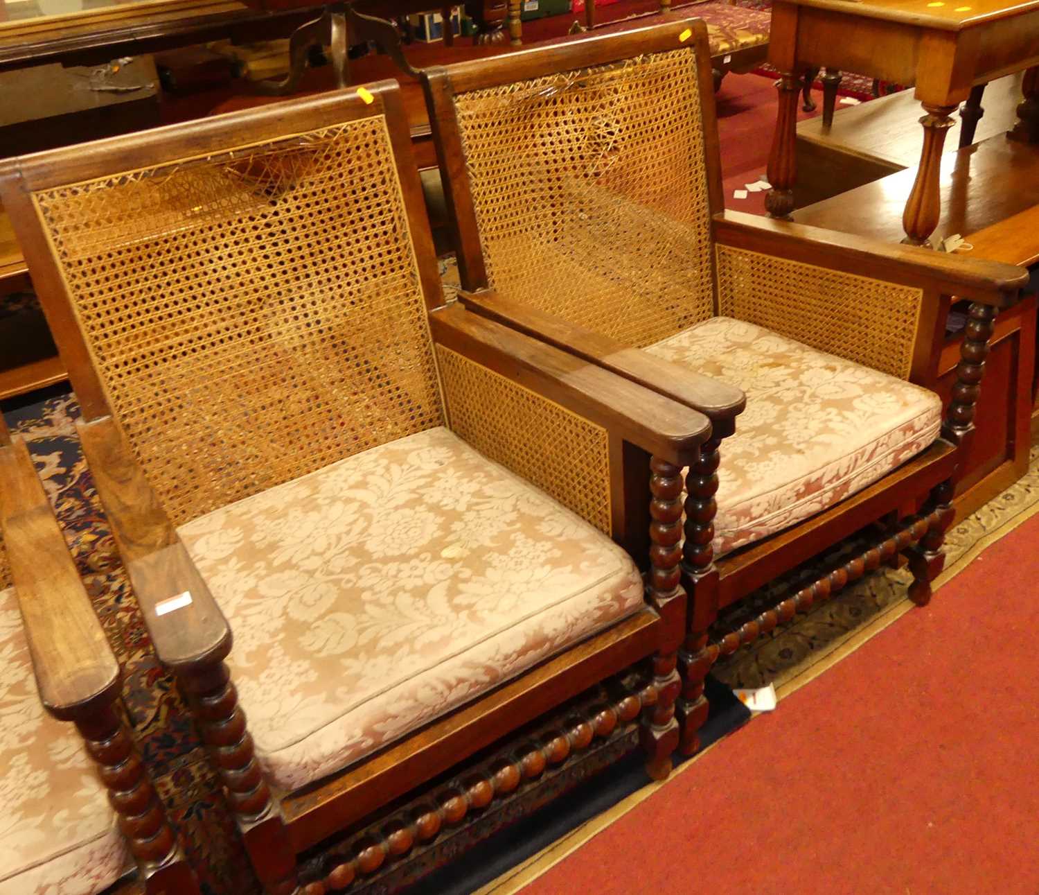 A pair of early 20th century indigenous hardwood and cane bergere chairs, raised on bobbin turned