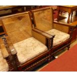 A pair of early 20th century indigenous hardwood and cane bergere chairs, raised on bobbin turned