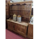 A light oak dresser, having two-tier open plate rack over base fitted with twin frieze drawers, over