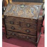A 19th century relief carved oak slopefront writing bureau, having a fitted interior over two