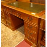 A contemporary yew wood and gilt-tooled green leather inset twin pedestal writing desk, having an