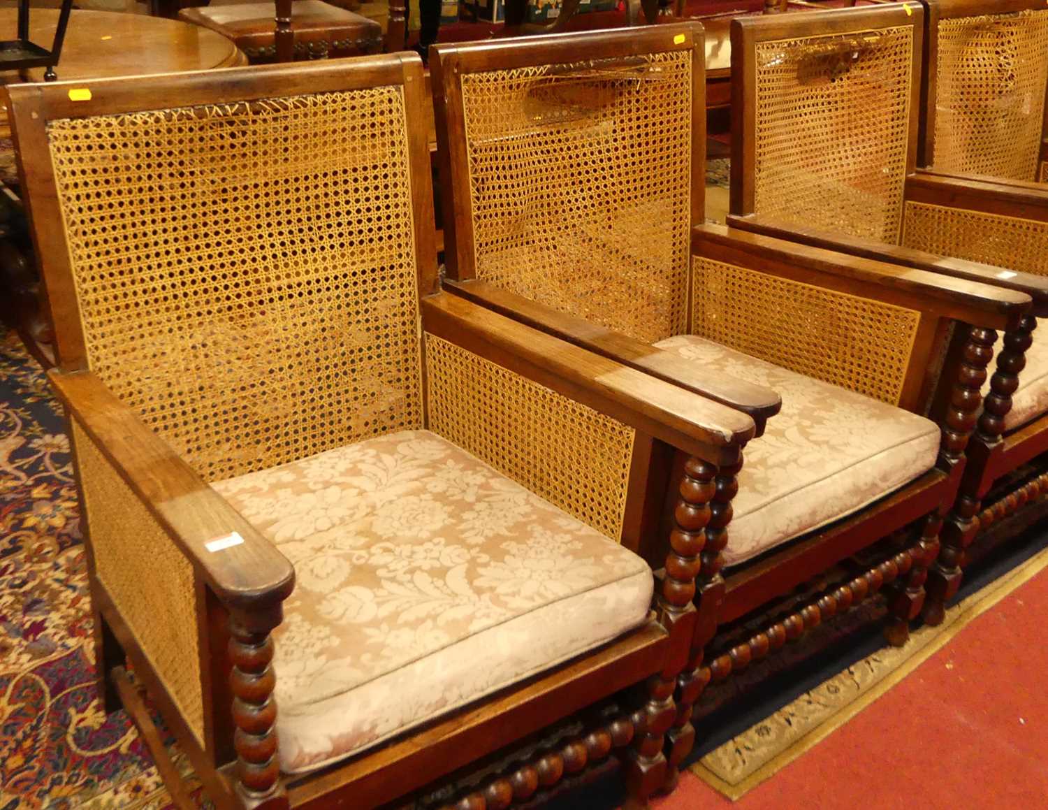 A pair of early 20th century indigenous hardwood and cane bergere chairs, raised on bobbin turned