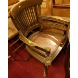 A 1930s oak slat back tub swivel desk chair, having a tan leather studded fixed pad seat, width