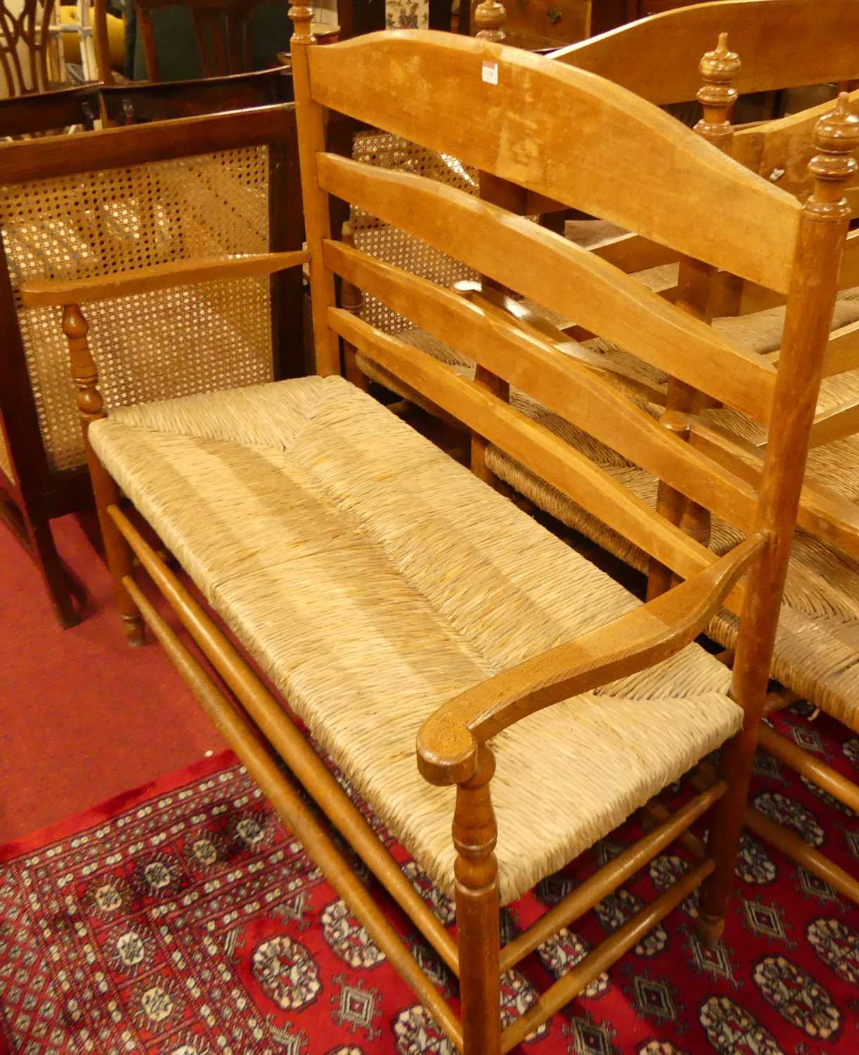 A set of four early 20th century elm and beech ladder back and rush seated two-seater settles,