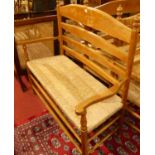 A set of four early 20th century elm and beech ladder back and rush seated two-seater settles,