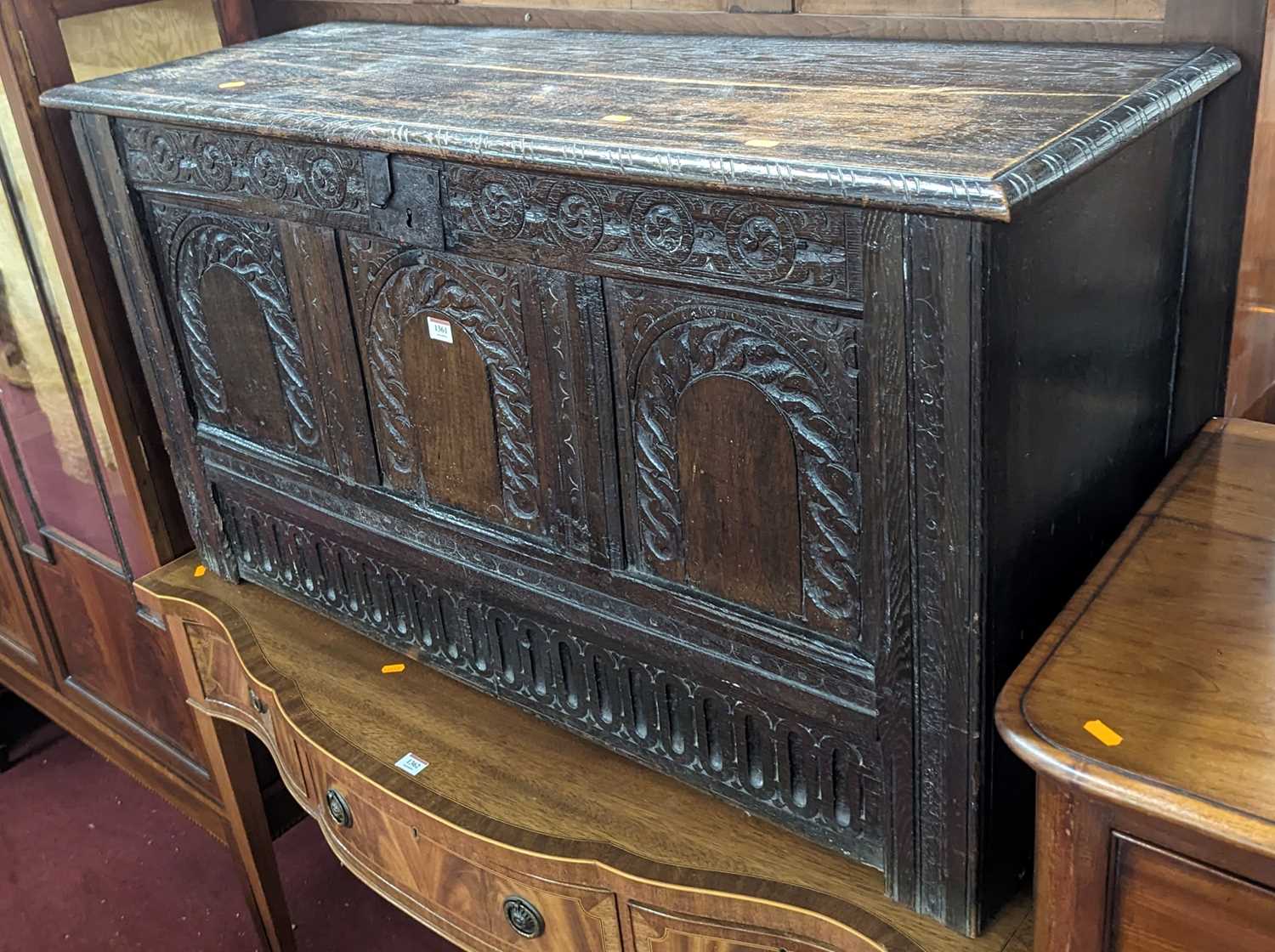 An 18th century joined oak three-panel hinge topped coffer, having later floral relief carved