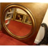 A contemporary gilt framed circular bevelled wall mirror, housed in a square frame with cushion