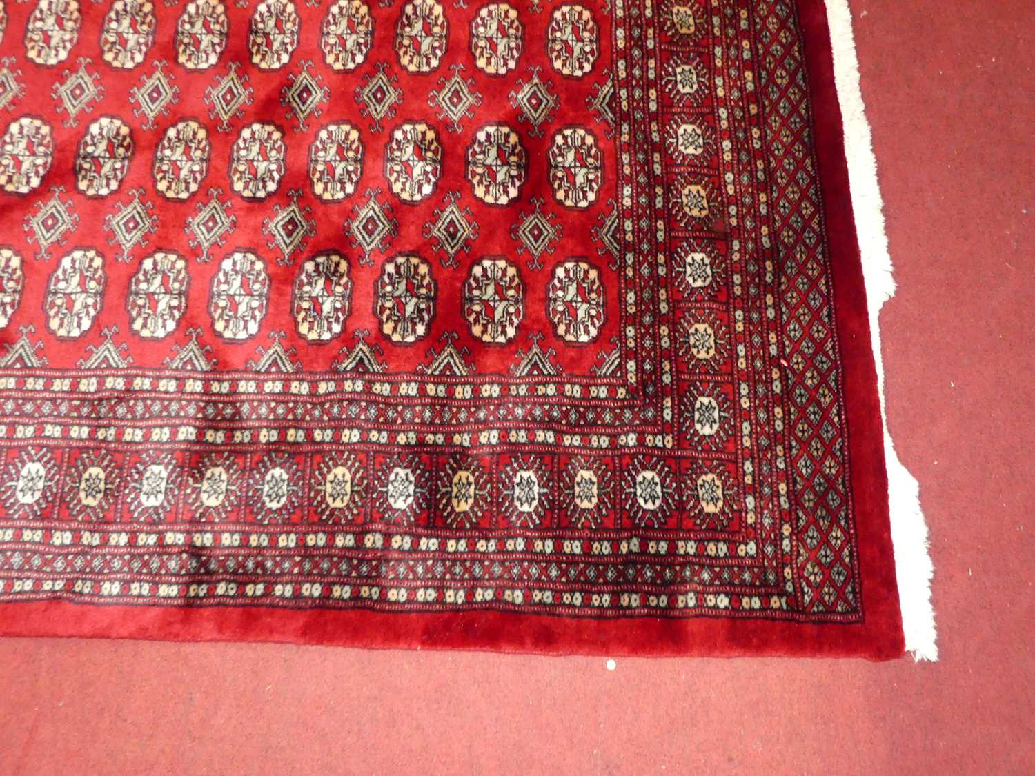 A Persian woollen red ground Bokhara rug, 242 x 154cm Rug is in excellent condition. Colours are - Image 2 of 4