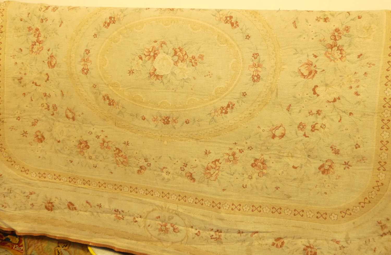 A Continental cream floral woven Aubusson rug Very faded. Some marks and light staining. Machine