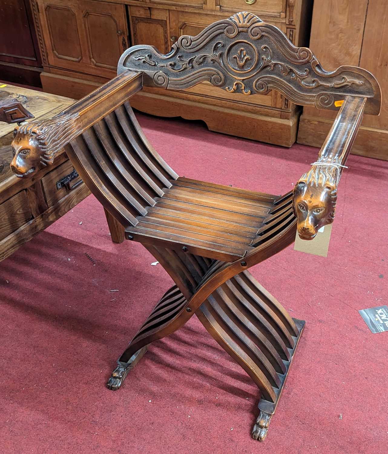 A contemporary Spanish stained beech X-frame folding elbow chair, with lions head arm terminals, w.