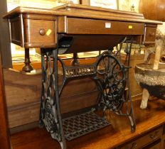 An early 20th century Singer treadle sewing machine table, the hinged cover with integral sewing