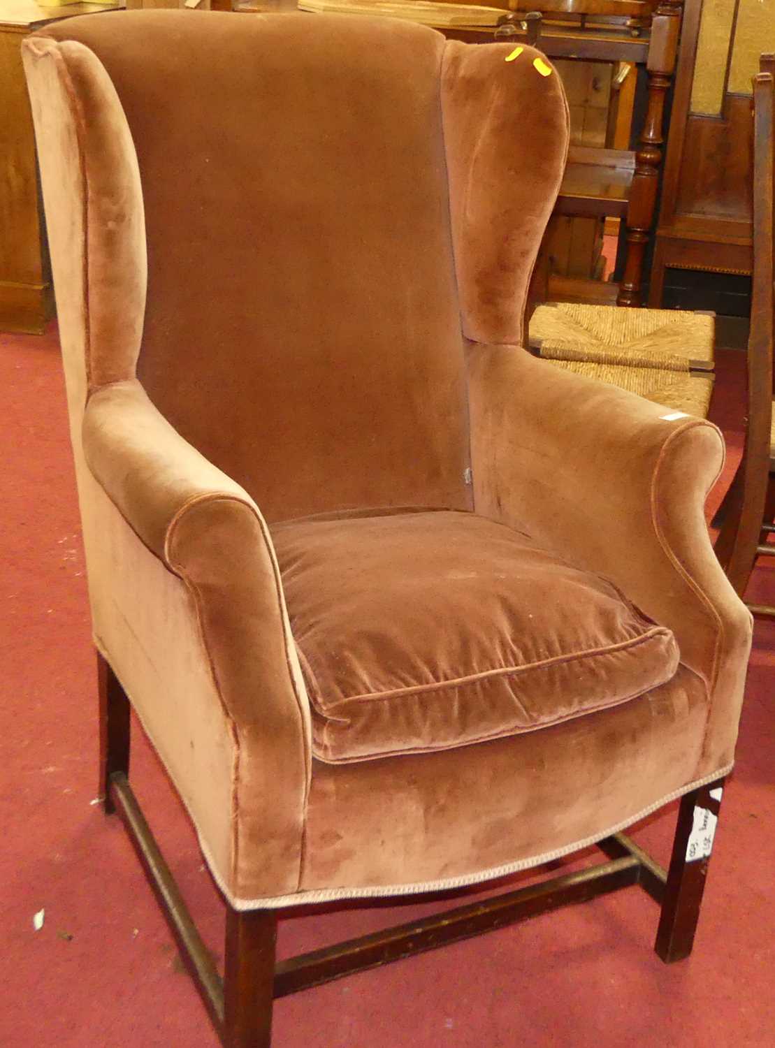 An early 20th century mahogany framed and pink dralon upholstered wing back armchair with squab