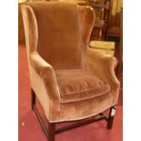 An early 20th century mahogany framed and pink dralon upholstered wing back armchair with squab