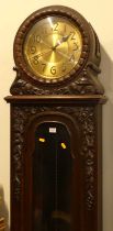 An early 20th century oak longcase clock, having a drum head top with brass Arabic dial, three-train