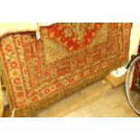 An Afghan red ground woollen table covering, having knotted and tasselled detail, 180 x 140cm