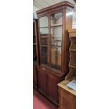 A mid-Victorian narrow mahogany round cornered bookcase cupboard, having twin glazed upper doors