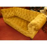 A circa 1900 and later mustard fabric button upholstered two-seater Chesterfield, raised on ring