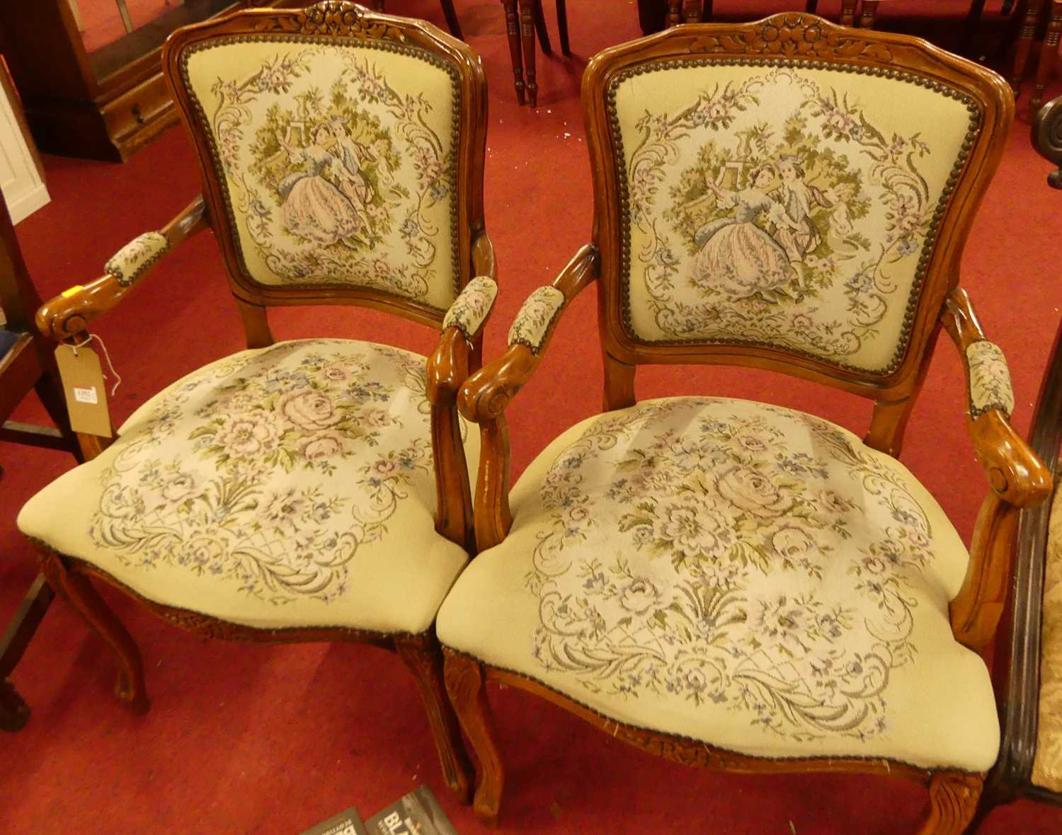 A pair of contemporary French walnut needlework floral and figural upholstered elbow chairs, in