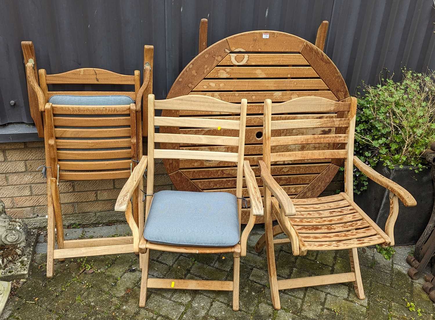 A contemporary slatted teak circular folding garden table, together with a matching set of three