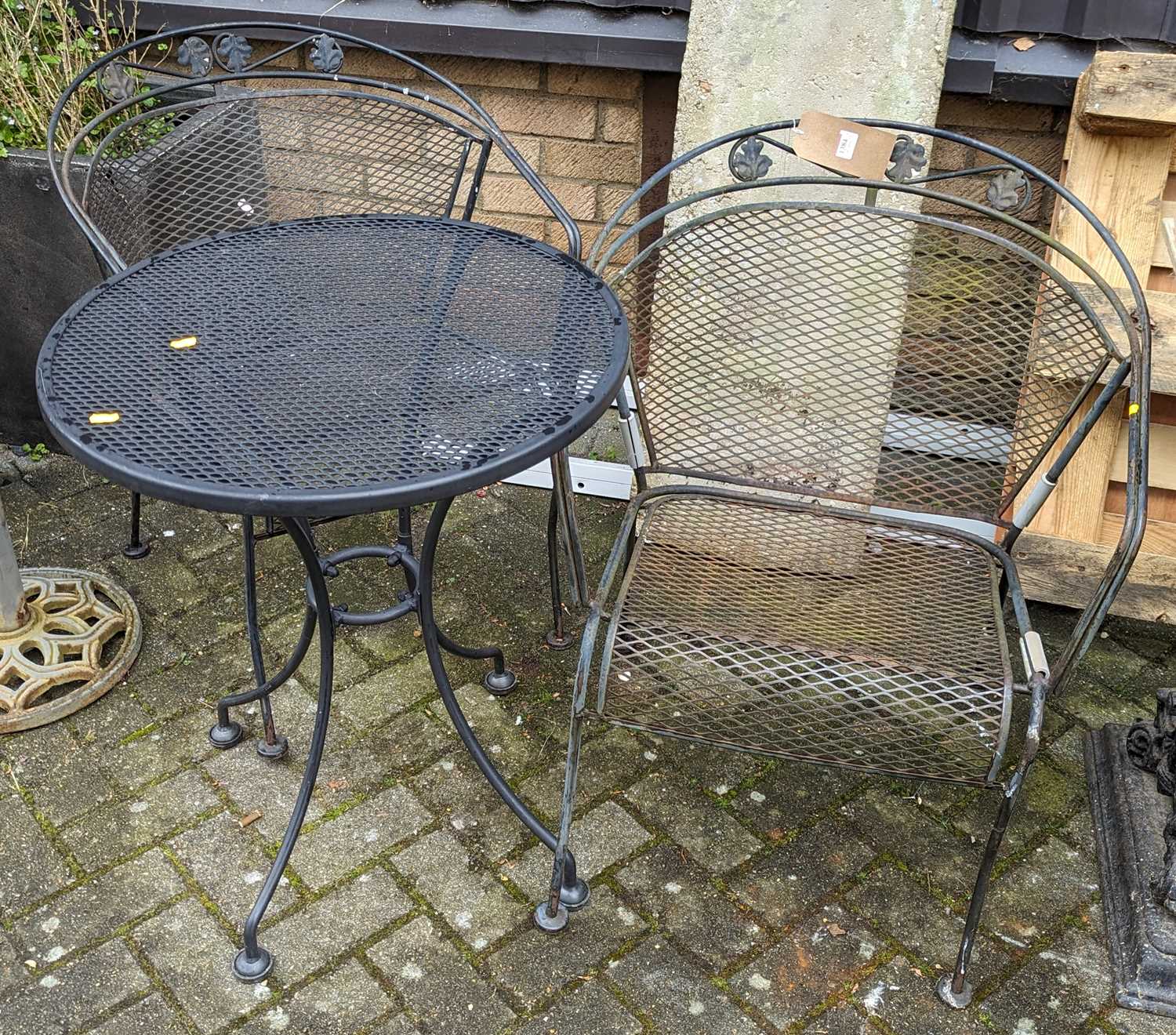 A black-painted wired metal circular patio table, together with a pair of similar tub patio elbow