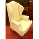 A contemporary cream floral fabric upholstered wingback scroll armchair, having squab cushion and