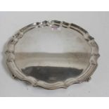 A George V silver salver, having a piecrust rim, standing upon four scroll feet, makers marks