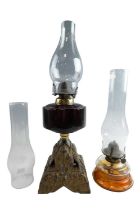 A cast iron and glass oil lamp together with a finger lamp and a spare glass chimney, former 48 cm