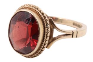A garnet dress ring, the facet-cut oval stone (approx 9 mm x 7 mm) bezel-set within a pair of cables