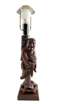 A Chinese carved hardwood figural table lamp depicting Liu Hai holding his three legged toad, both