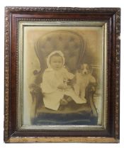 A portrait of a young child dressed in white, sat on an armchair with a puppy, photographic print,