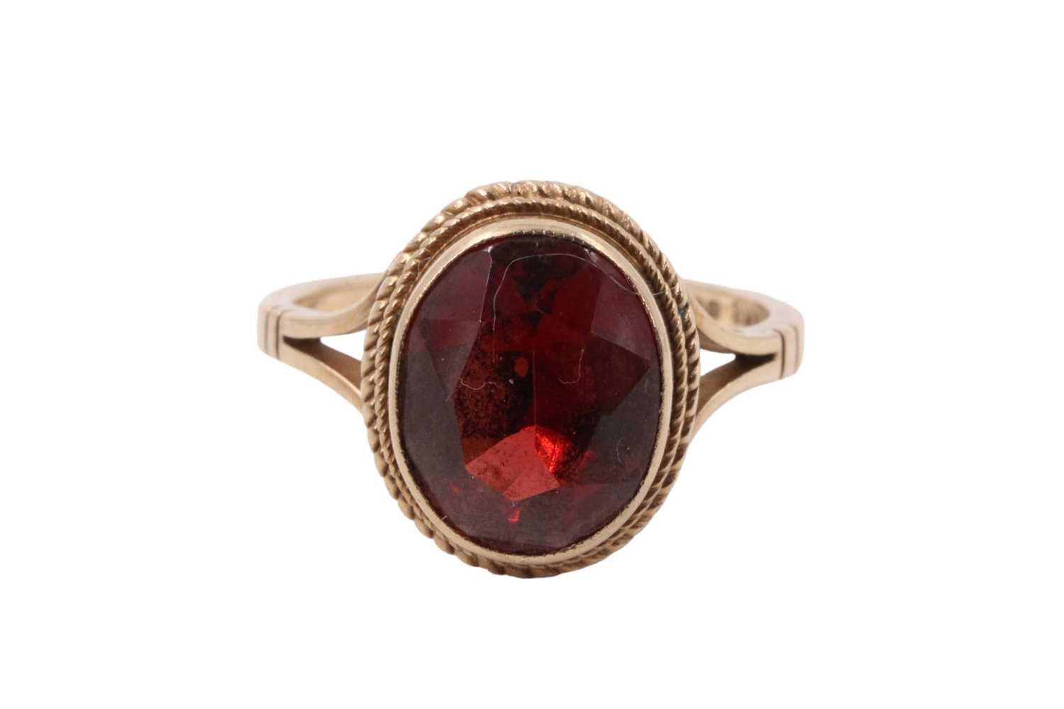 A garnet dress ring, the facet-cut oval stone (approx 9 mm x 7 mm) bezel-set within a pair of cables - Image 2 of 5