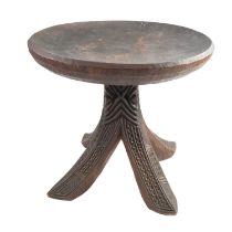 An African carved hardwood stool, having a concave top, carved and raised on a carved four leg