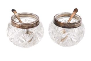 A pair of early 20th Century silver collared pressed glass salt cellars and silver salt spoons,