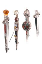 Four early-to-mid 20th century polished hardstone white metal kilt pins, in the form of a sword