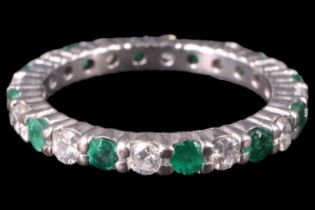A contemporary diamond and emerald eternity ring, having 12 brilliant cut diamonds (approximately